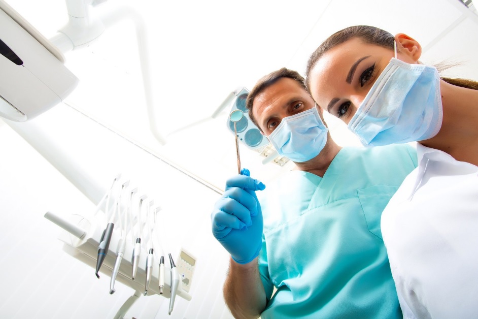 Two masked dental practitioners viewed from a dental chair
