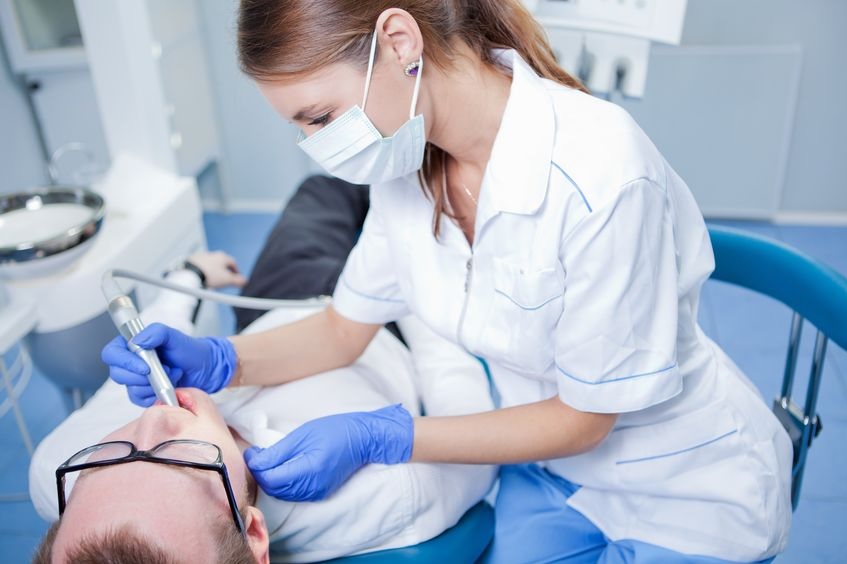 A dental practitioner examining a patient in a dental chair