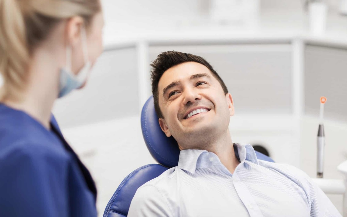 A patient speaking with a dental practitioner beside a dental chair